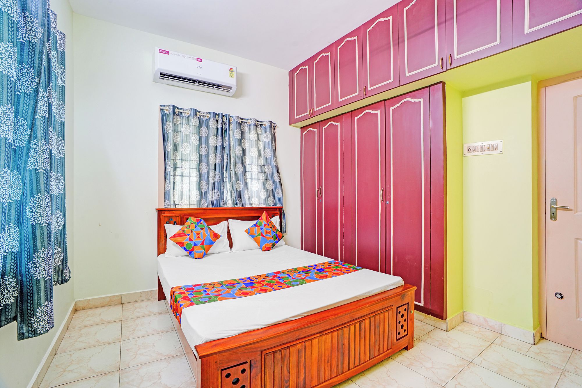 Quarto com cama, ar condicionado, guarda-roupa e porta.