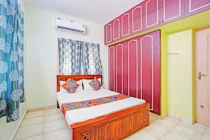 Un dormitorio con cama, aire acondicionado, armario y puerta.