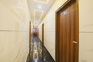 A hotel corridor with marble walls, a black floor, and wooden doors. - FabHotel Metro Star (New Delhi)