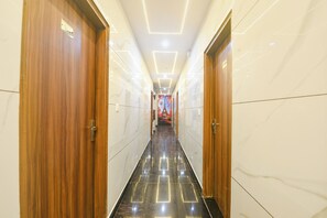 A hotel hallway with wooden doors, marble walls, and a reflective floor.