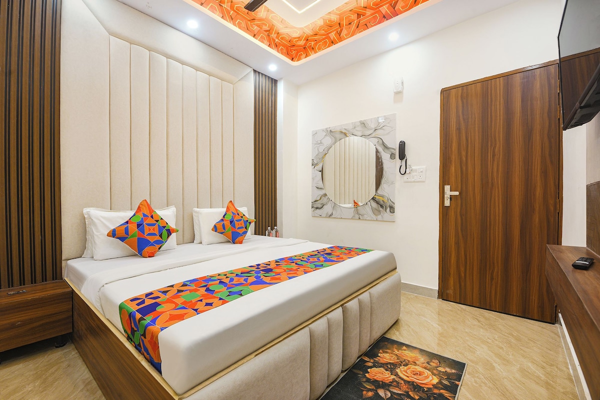 A bedroom with a bed, pillows, a bedside table, a mirror, a wardrobe, and a ceiling light fixture.