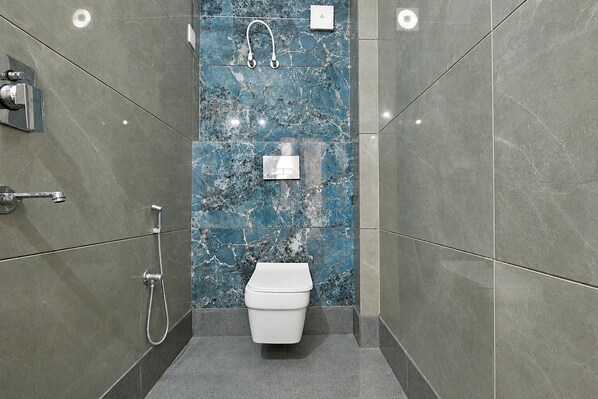 A modern bathroom with a toilet, a shower, and a hand dryer.