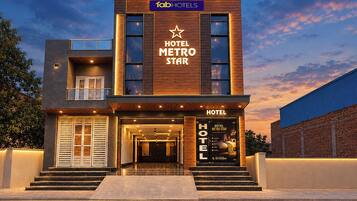 Um hotel moderno com uma placa grande exibindo 'HOTEL METRO STAR' e um logotipo em forma de estrela.
