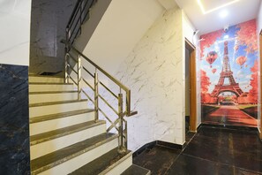 A marble staircase with a metal handrail leading to a room with a mural of the Eiffel Tower.