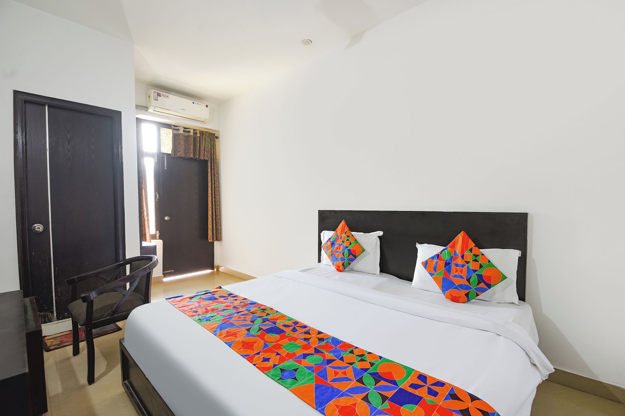 Quarto de hotel com cama, escrivaninha e ar condicionado.