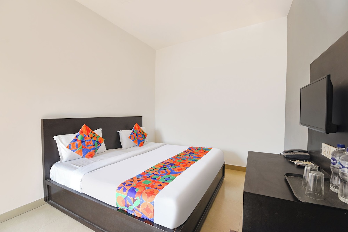 Una habitación de hotel con cama, televisión, escritorio y una botella de agua.