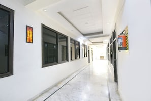 A long, narrow hallway with white walls and large windows on one side.