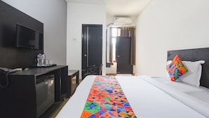 Ein Hotelzimmer mit Bett, Schreibtisch, Fernseher und Klimaanlage.
