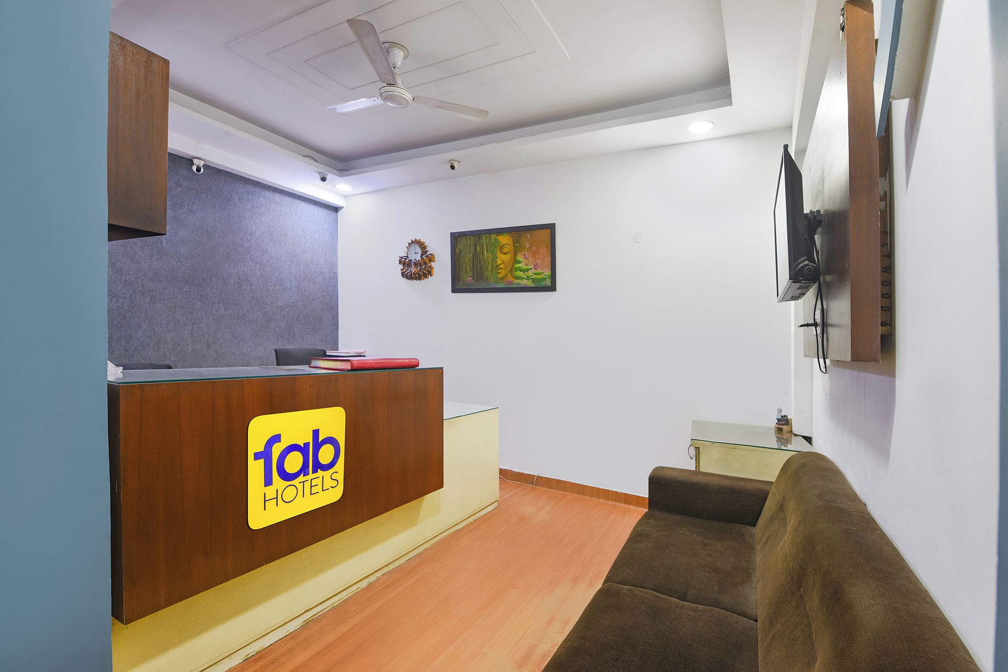 Un espace d’accueil avec un bureau en bois, une horloge, un tableau et un canapé.