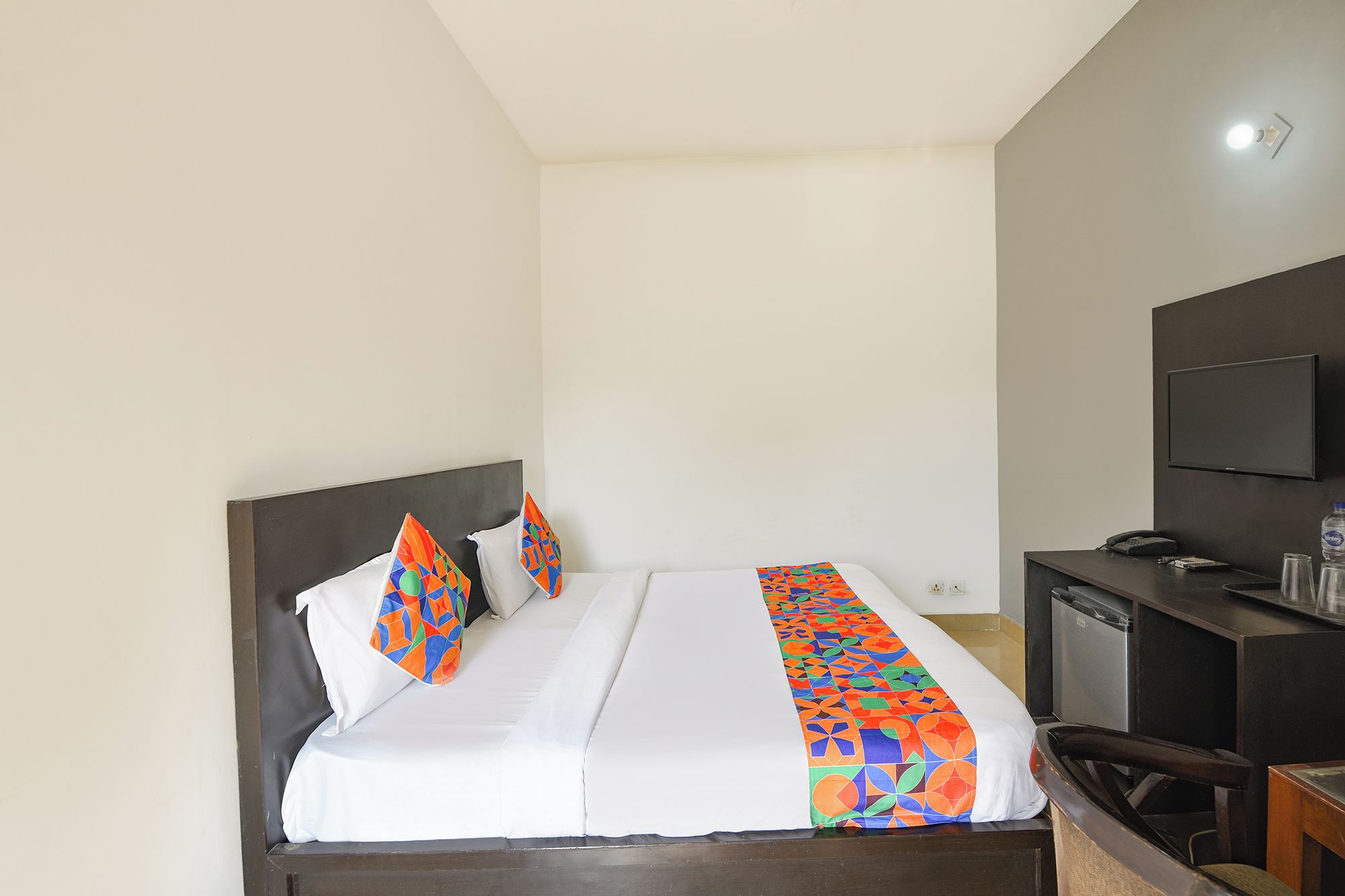 Une chambre d’hôtel équipée d’un lit, d’un bureau, d’une chaise, d’une télévision et d’un téléphone.