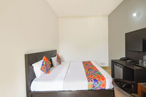 Ett hotellrum med en säng, ett skrivbord, en stol, en TV och en telefon.