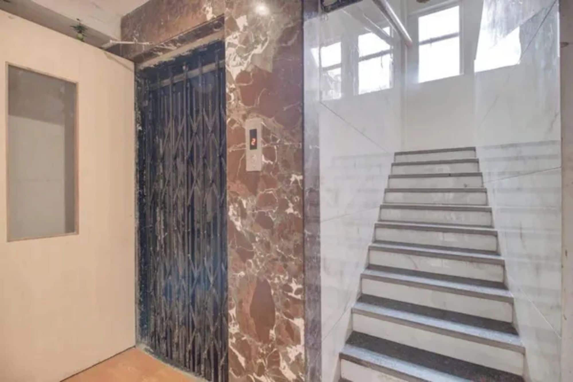 A hallway with a marble wall, a door, and a staircase.