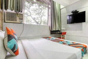 A hotel room with a bed, a desk, a TV, and a window with curtains. - FabHotel Spring Residency (Mumbai)
