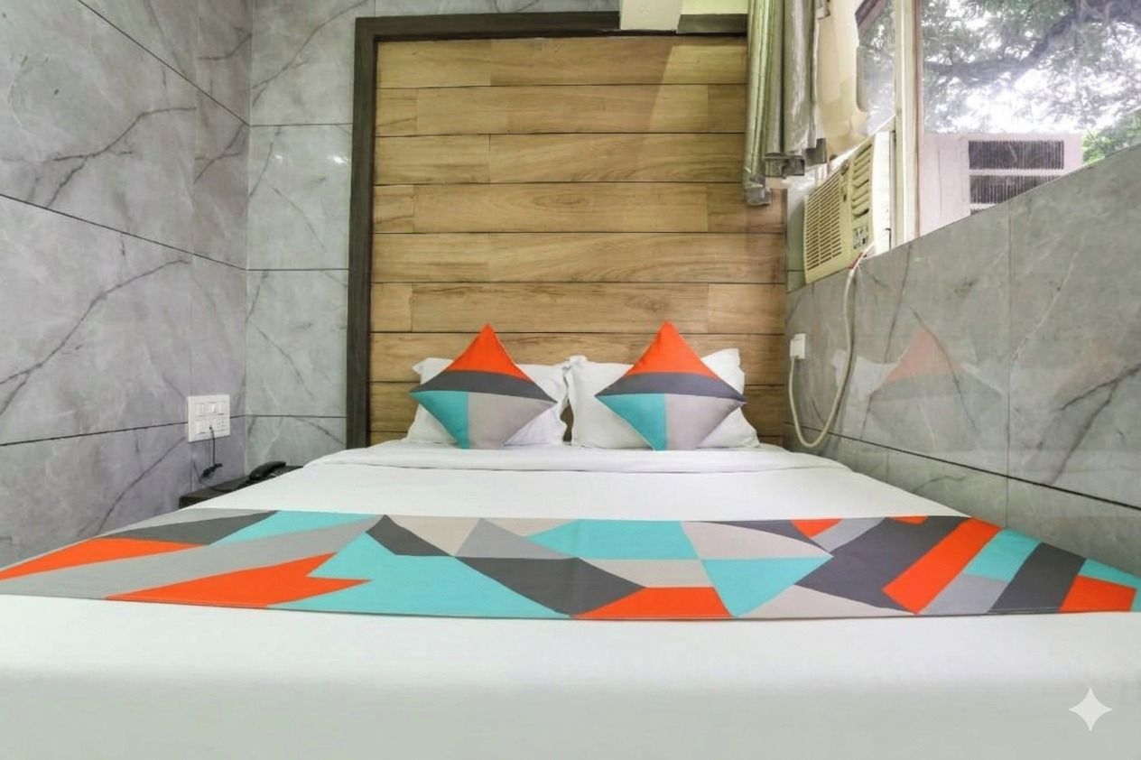 A hotel room with a wooden headboard, a bed with a geometric-patterned bedspread, and two pillows with a geometric design.