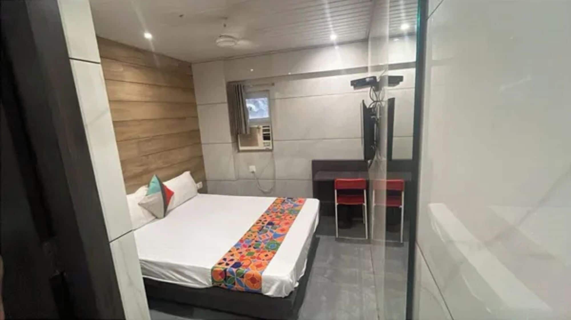 Ein modernes Hotelzimmer mit Bett, kleinem Schreibtisch und Duschbereich.