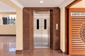An elevator with a metallic finish, a green floor indicator, and a decorative panel with a geometric pattern. - FabHotel Prime City Central (Visakhapatnam)