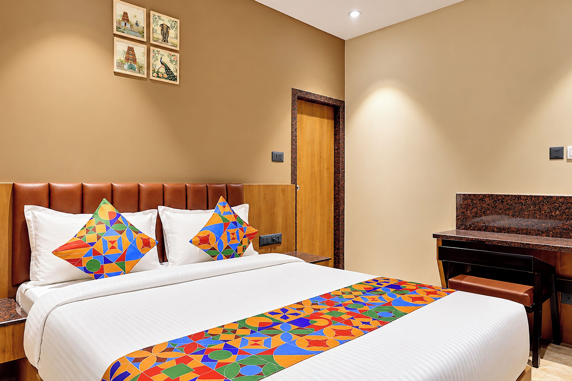 A hotel room with a bed, a desk, and a door.
