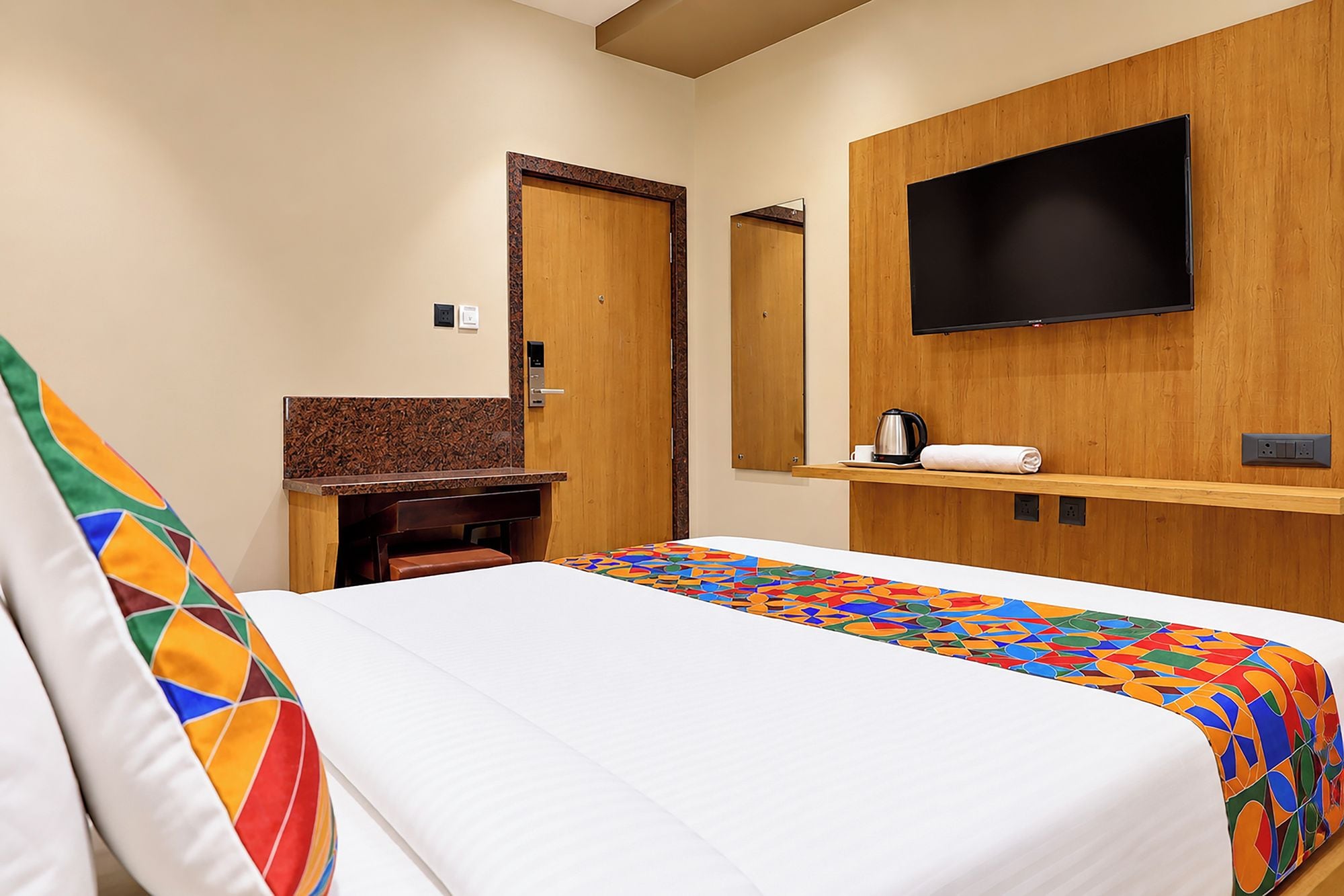 Habitación de hotel con cama, escritorio, televisor y cafetera.
