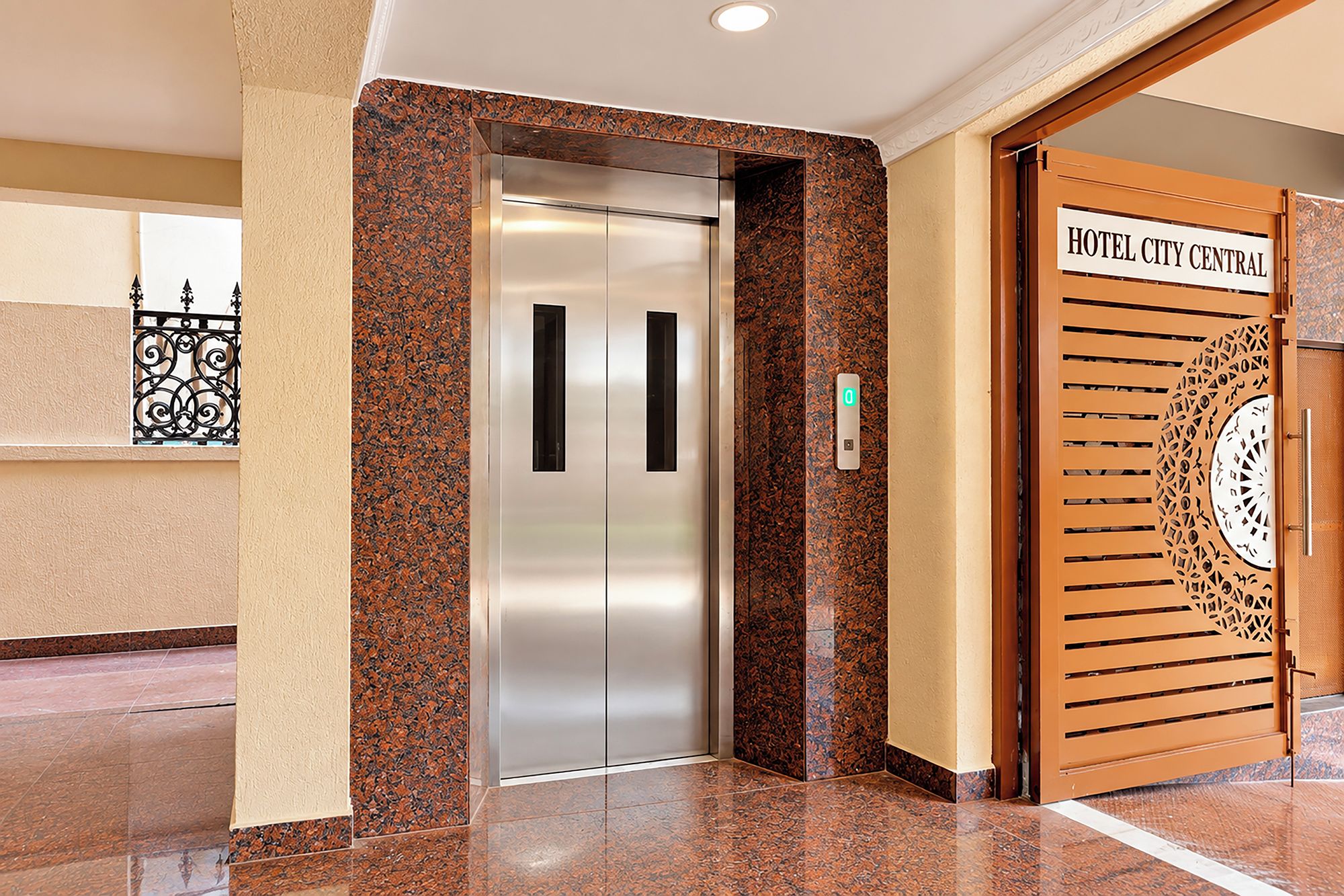 Entrada de hotel con un ascensor moderno y una puerta decorativa con un letrero.