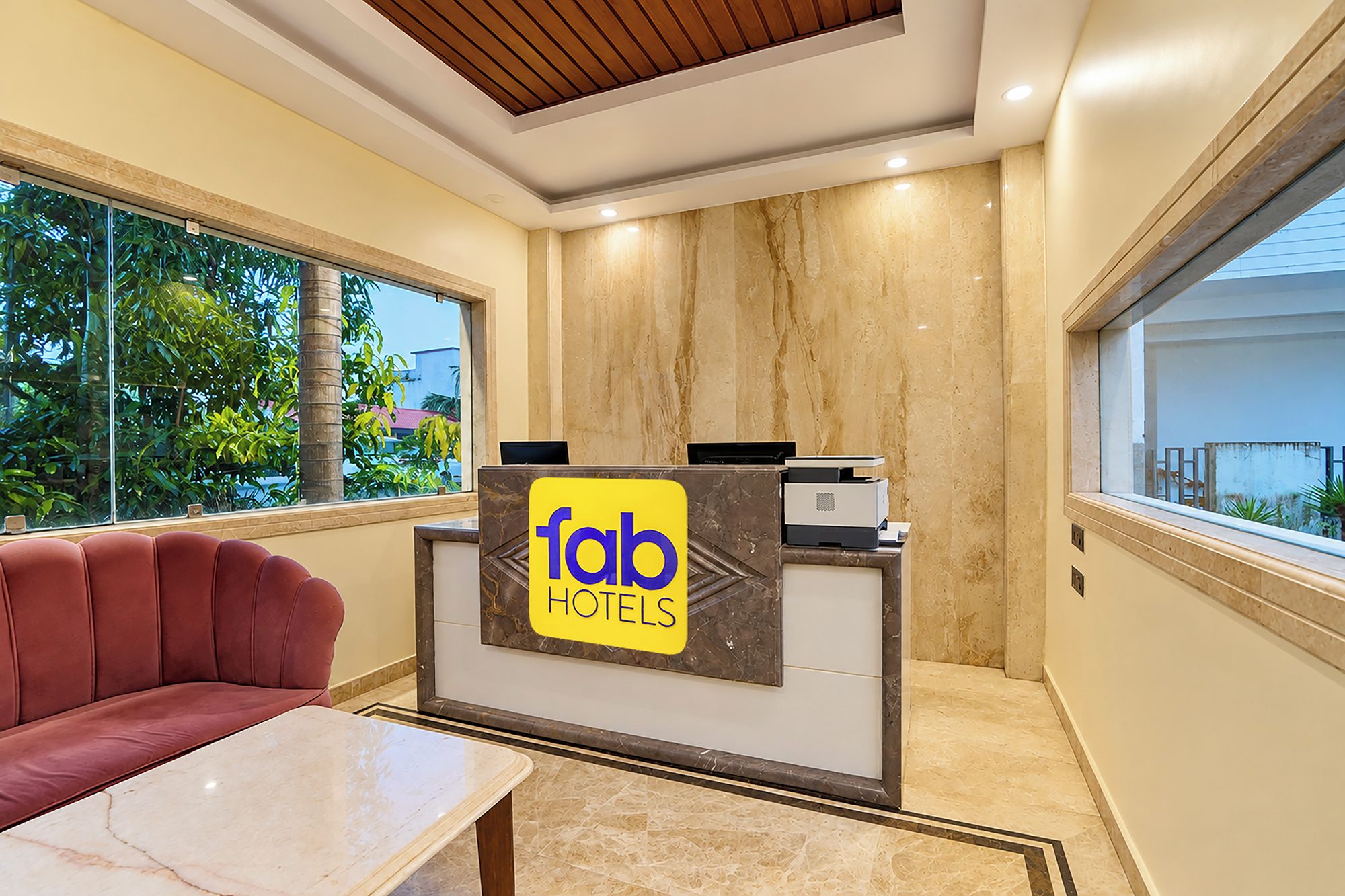 A hotel reception desk with a sign reading 'tab hotels,' a leather sofa, and a marble-topped table.