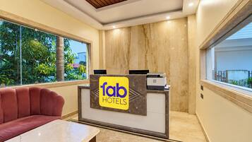 A hotel reception desk with a sign reading 'tab hotels,' a leather sofa, and a marble-topped table.