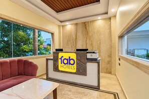 A hotel reception desk with a sign reading 'tab hotels,' a leather sofa, and a marble-topped table. - FabHotel Rajdhani Heritage (Ranchi)