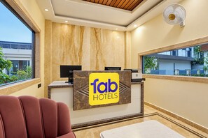 A hotel reception area with a reception desk, a computer, and a seating area.
