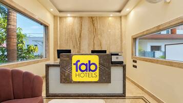 Un comptoir d’accueil avec une enseigne « Tab Hotels », un plafond en bois et une vue sur l’extérieur.