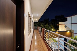 A corridor with a wooden floor leading to a balcony with a railing.