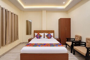 A hotel room with a bed, a wardrobe, a desk, and a chair.