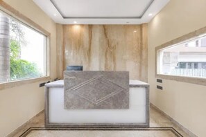 A reception desk with a marble top and a framed artwork above it.