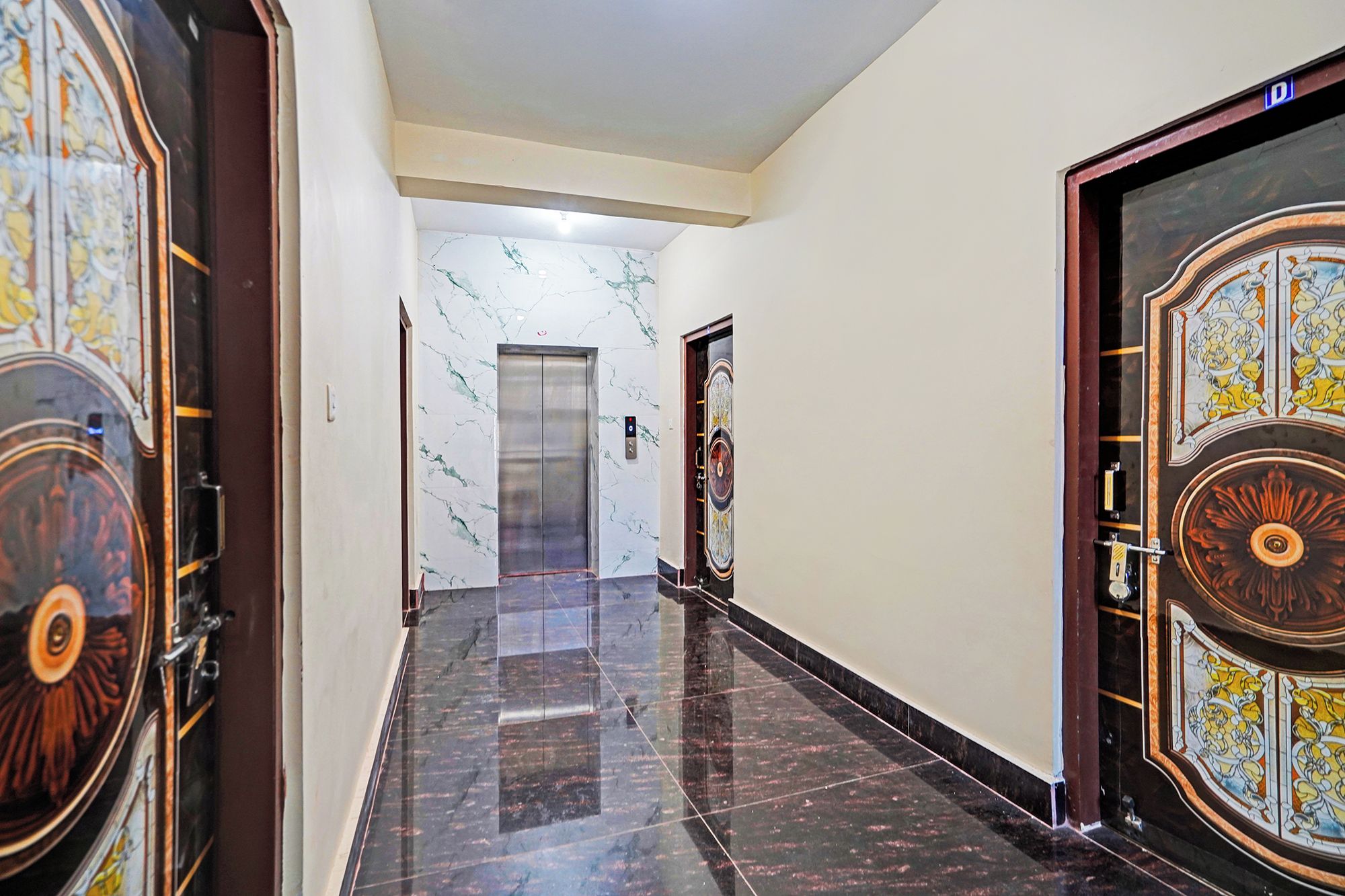 A corridor with marble walls and doors, leading to an elevator.