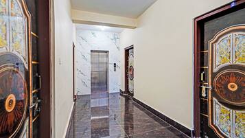 A corridor with marble walls and doors, leading to an elevator.
