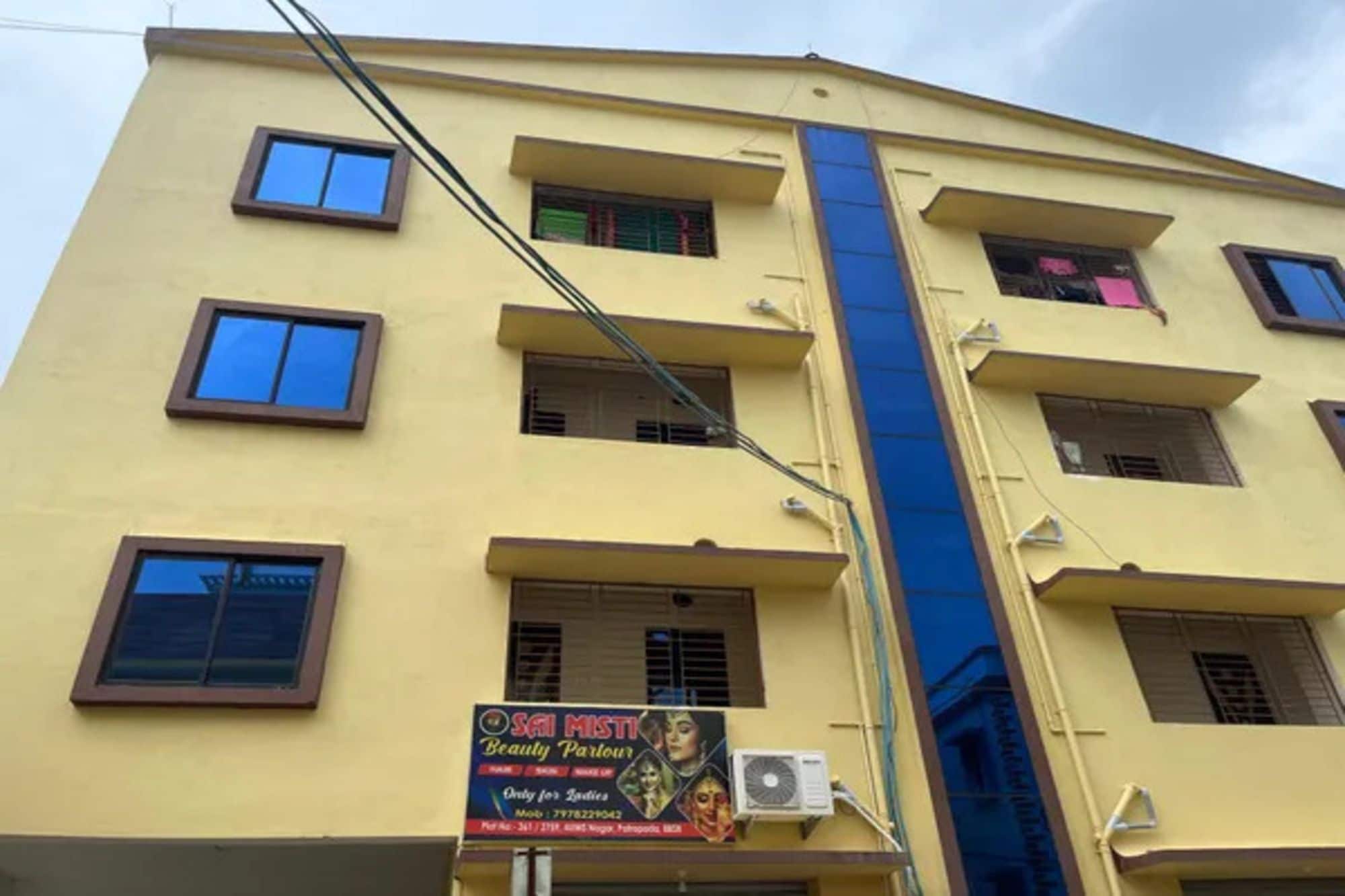 A multi-story building with a yellow facade, multiple windows, and a sign for a beauty salon.