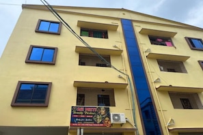 Un edificio de varios pisos con fachada amarilla, múltiples ventanas y un letrero de salón de belleza.