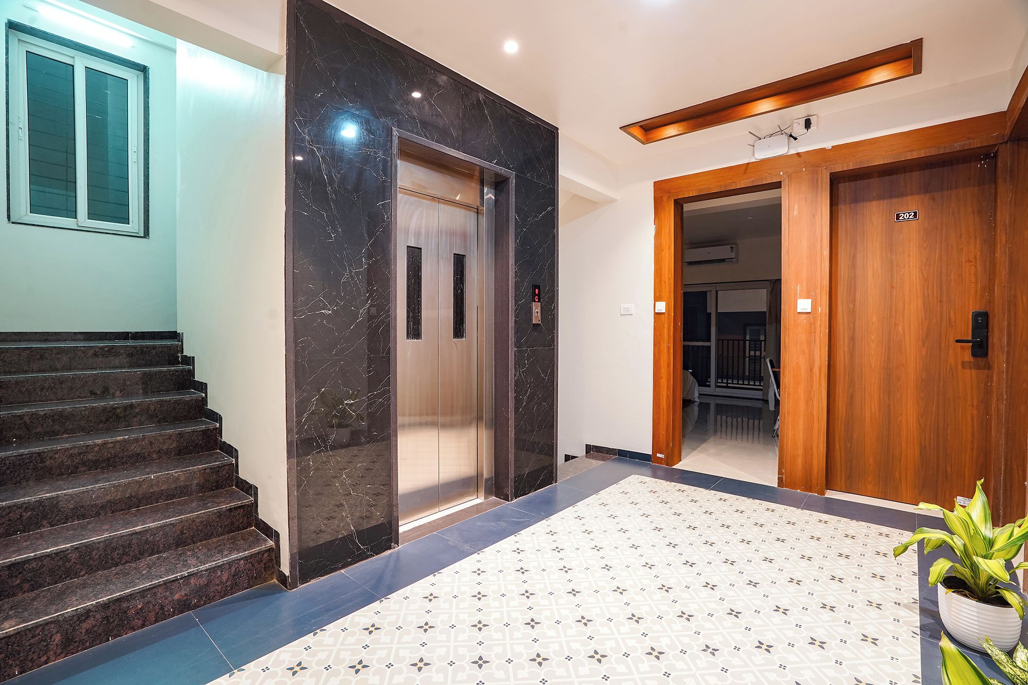 A modern interior with a marble elevator, a wooden door, and a patterned floor.