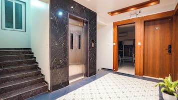 A modern interior with a marble elevator, a wooden door, and a patterned floor.