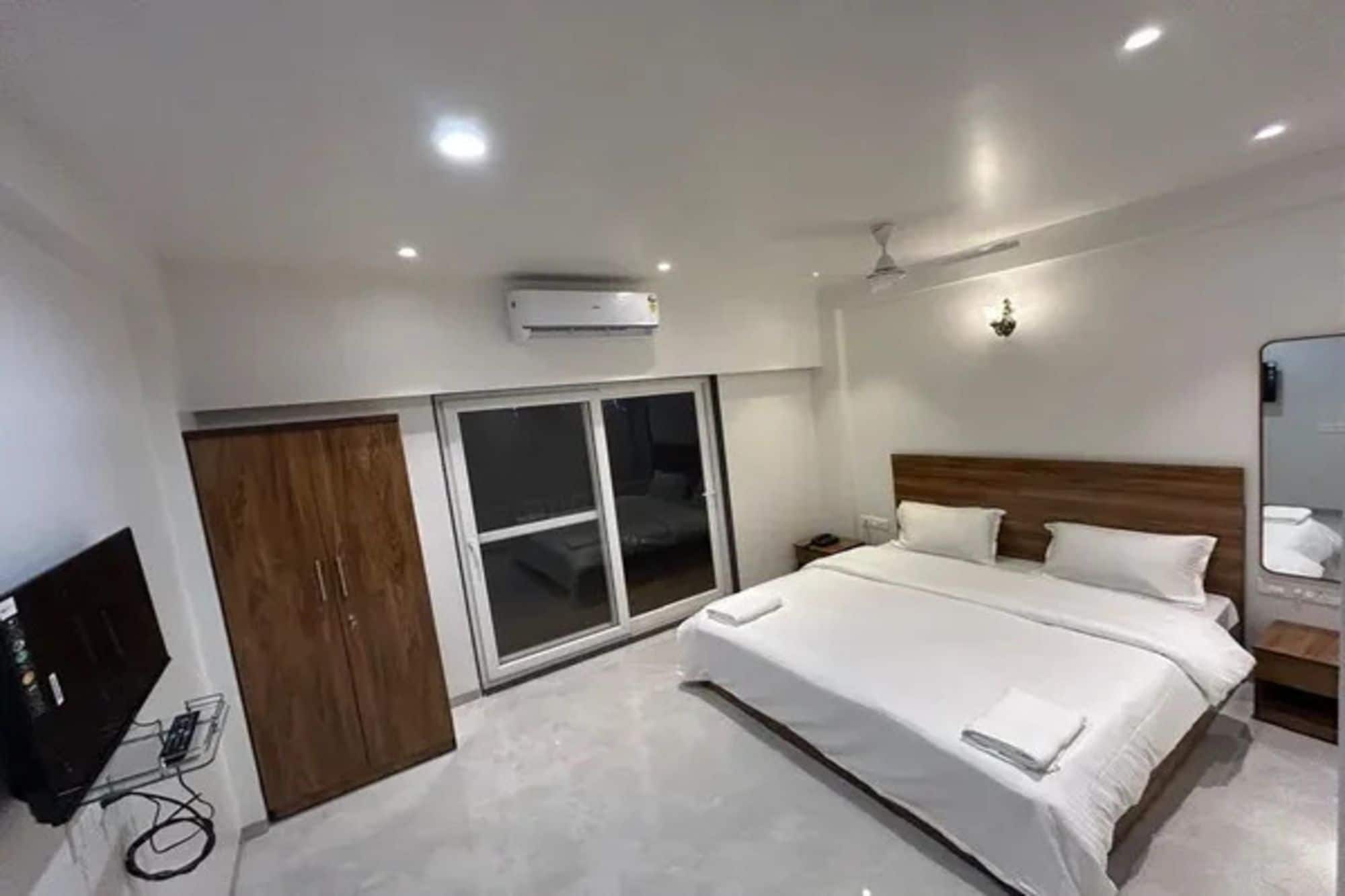 Quarto de hotel com uma cama, televisão e porta de correr.