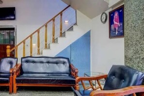 A staircase with wooden balusters, a blue wall, and a black leather sofa with wooden armrests.