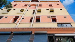 Un edificio de varios pisos con fachada plana, amplias ventanas y un conducto de aire acondicionado central.