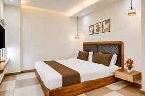 A hotel room with a bed, bedside table, and a television.
