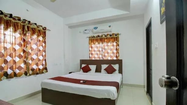 Quarto de hotel com cama, cortinas, porta e janela.
