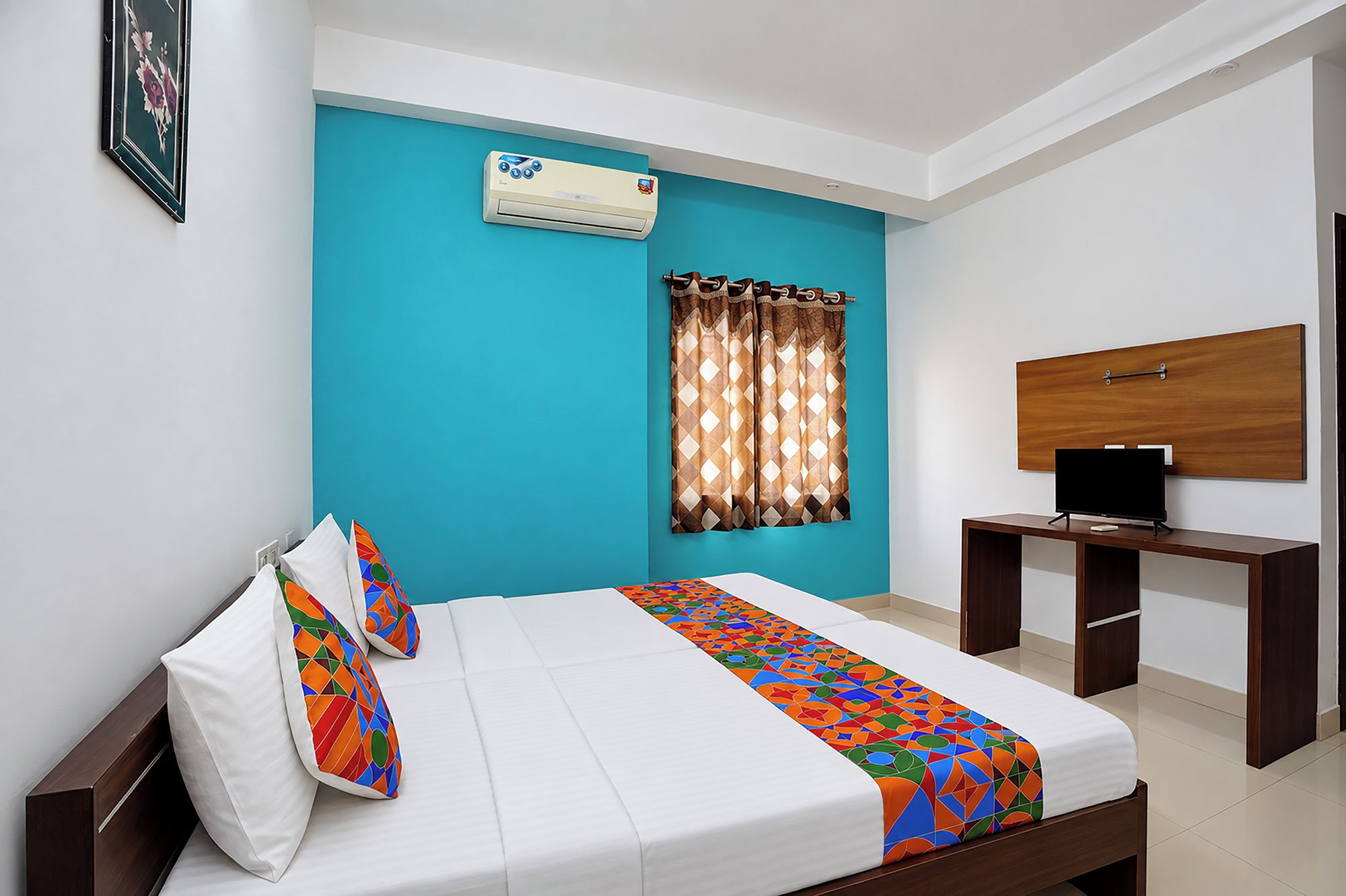Une chambre d’hôtel avec un lit, un bureau, une télévision et une fenêtre avec des rideaux.