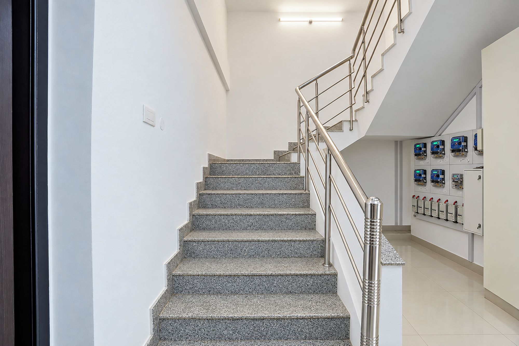 Una escalera con barandilla de metal que conduce a una plataforma con cuadros eléctricos.