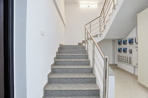 Una escalera con barandilla de metal que conduce a una plataforma con cuadros eléctricos.