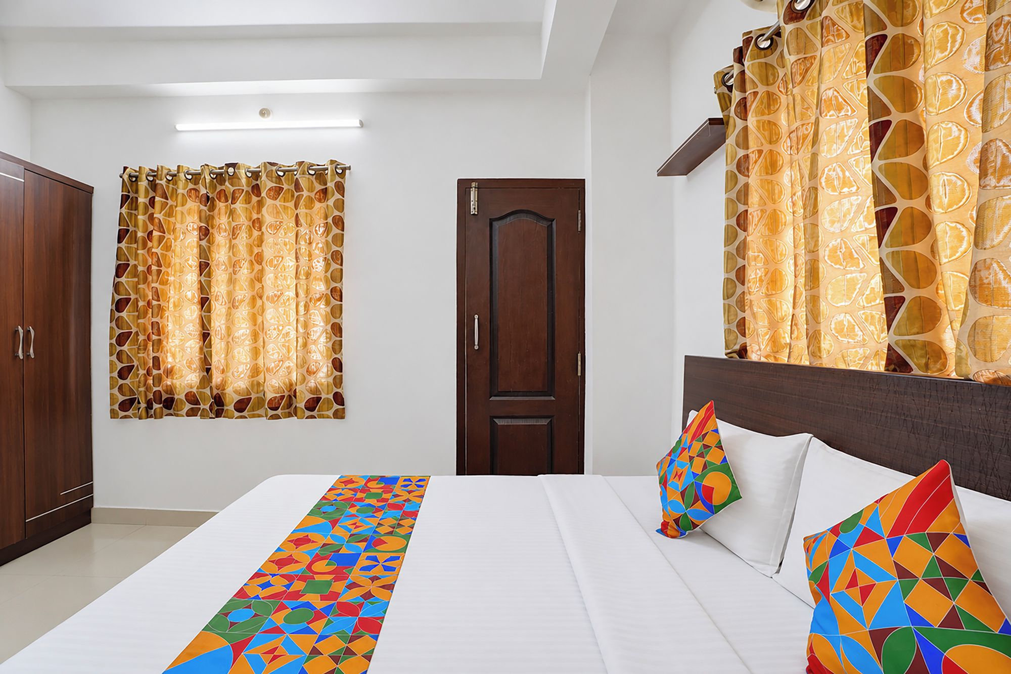 Una habitación de hotel con cama, armario, puerta y cortinas.