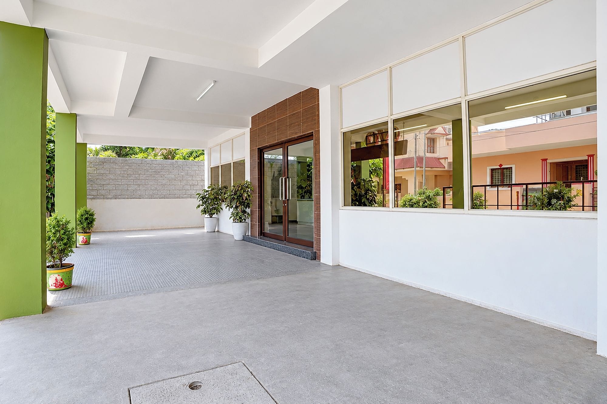 Un bâtiment moderne avec une façade épurée, un toit plat, de grandes fenêtres et des plantes en pot.