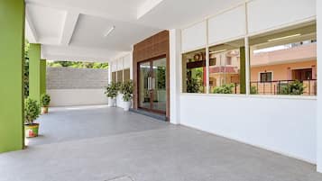 Un bâtiment moderne avec une façade épurée, un toit plat, de grandes fenêtres et des plantes en pot.