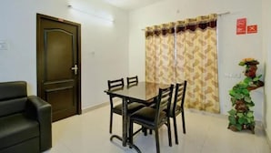 Quarto com mesa de jantar e cadeiras, ventilador de teto, porta e cortina.
