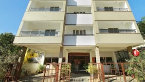 Um edifício de vários andares com fachada plana, varandas em cada pavimento e entrada com portão.